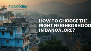 A panoramic, high-angle view of a densely built city in a valley at dusk, with mountains in the background. The text overlay asks: "HOW TO CHOOSE THE RIGHT NEIGHBORHOOD IN BANGALORE?".