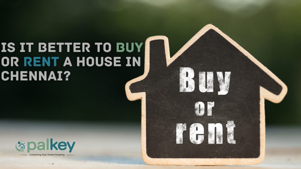 A miniature, house-shaped chalkboard sign standing upright with the words "Buy or Rent" written on it. The text asks: "IS IT BETTER TO BUY OR RENT A HOUSE IN CHENNAI?".