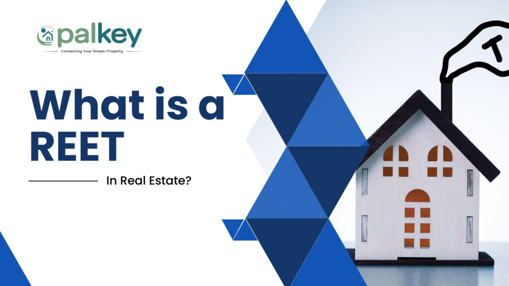 A graphic with the text "What is a REIT In Real Estate?". The "Opalkey" logo is in the top left corner. The image features a white miniature house with a flag on top showing a 'T'. The right side of the graphic has a blue triangular pattern.