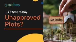 A promotional graphic for "Opalkey," a real estate service, with the question "Is it Safe to Buy Unapproved Plots?". The image features a miniature house model with a "Sale Pending" sign in front of it, and a hand is visible, suggesting a transaction. The background is dark with a gold/yellow section at the bottom.