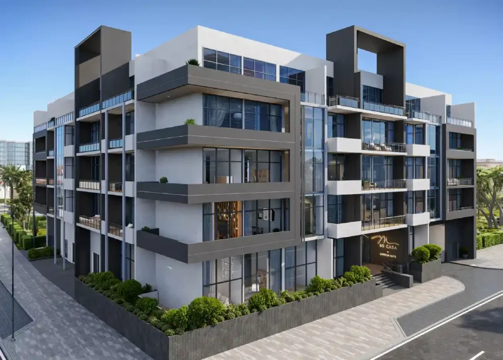 A digital rendering of a modern, multi-story residential building named "Mi Casa" with a contemporary design featuring large glass windows, dark gray accents, and expansive balconies. The ground floor entrance is lined with lush greenery and a paved sidewalk.