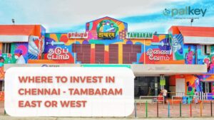 A promotional graphic for Opalkey with the text "WHERE TO INVEST IN CHENNAI - TAMBARAM EAST OR WEST". The background features the colorful, mural-painted Tambaram Railway Station facade, a major transit hub in South Chennai, symbolizing connectivity and local growth.